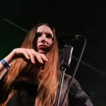 Florence Shaw of Dry Cleaning at the microphone in green stage light