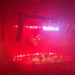Fontaines D.C. performing in an arena under red lighting with the band's logo behind them