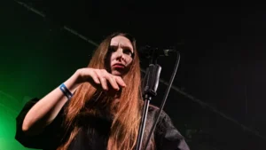 Florence Shaw of Dry Cleaning at the microphone in green stage light
